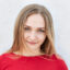 Blonde female in red sweater looking confidently into camera having mysterious look. Cute freckled woman with appealing appearance having assured look while posing against white background in studio